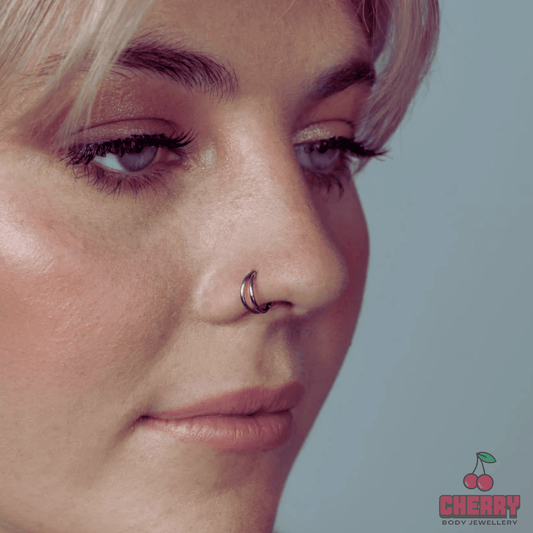 Close-up of a person wearing a nose ring with 'Cherry Body Jewellery' logo.