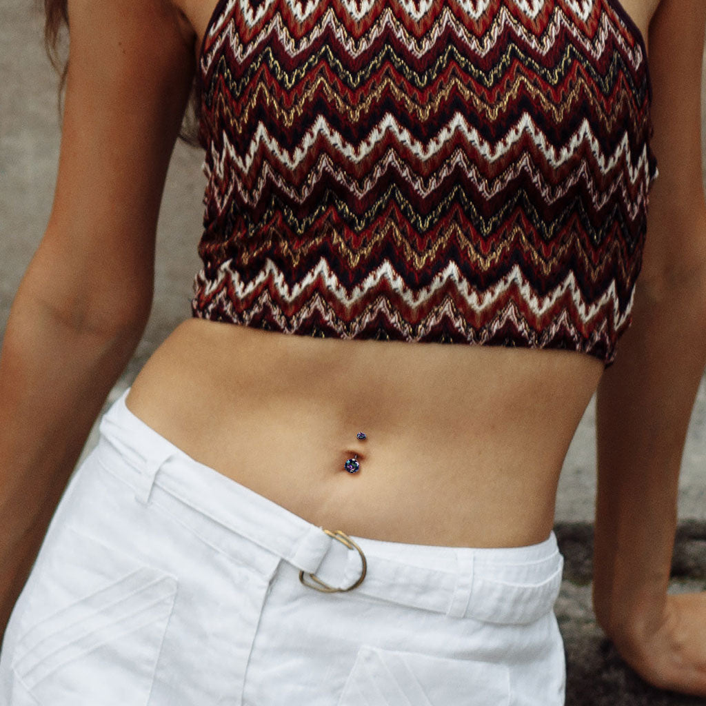 Person wearing a patterned top and white pants with a visible belly button piercing.